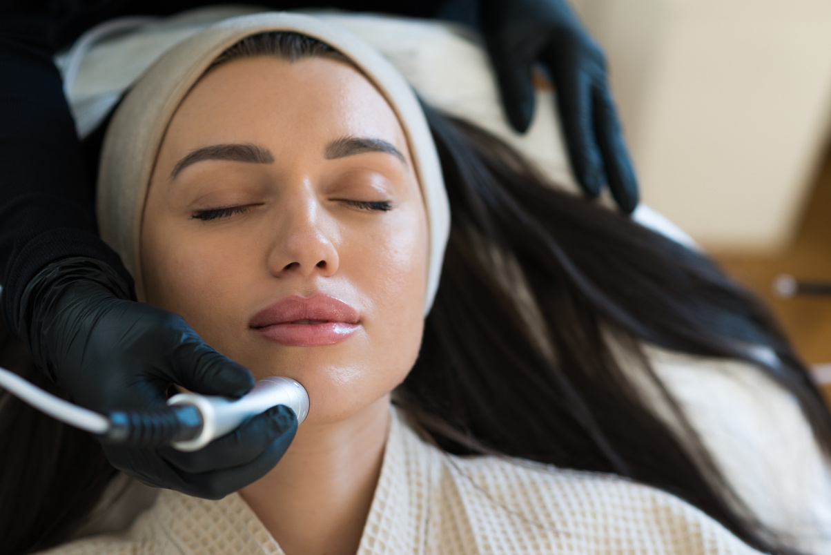 Professional female cosmetologist doing Hydrafacial procedure in Cosmetology clinic. Stock photo